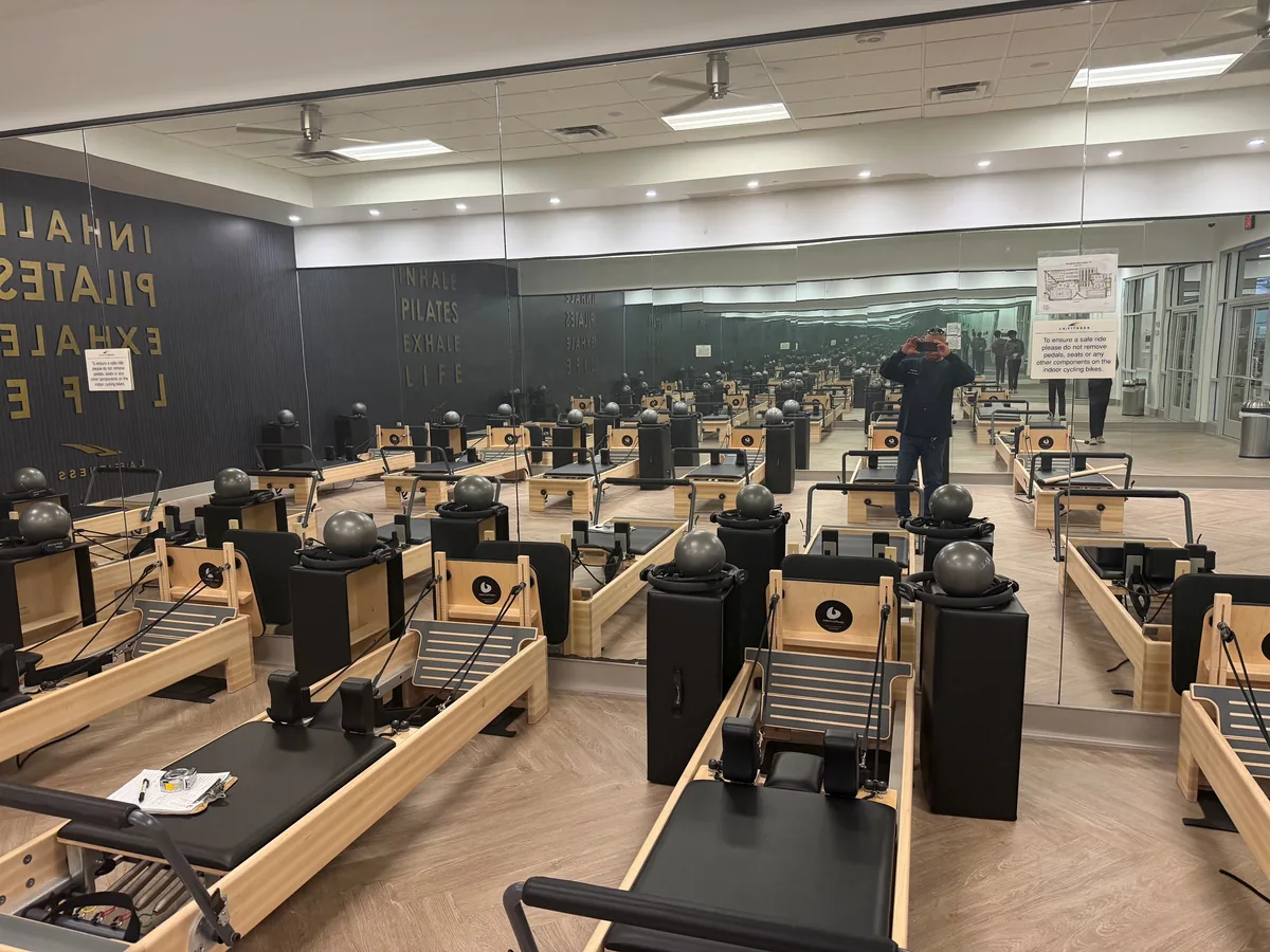 Commercial mirror wall reflecting exercise equipment in a Pilates studio.