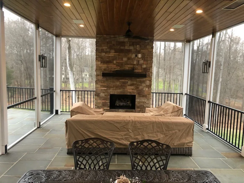 Screened porch with a stone fireplace and wooded views.