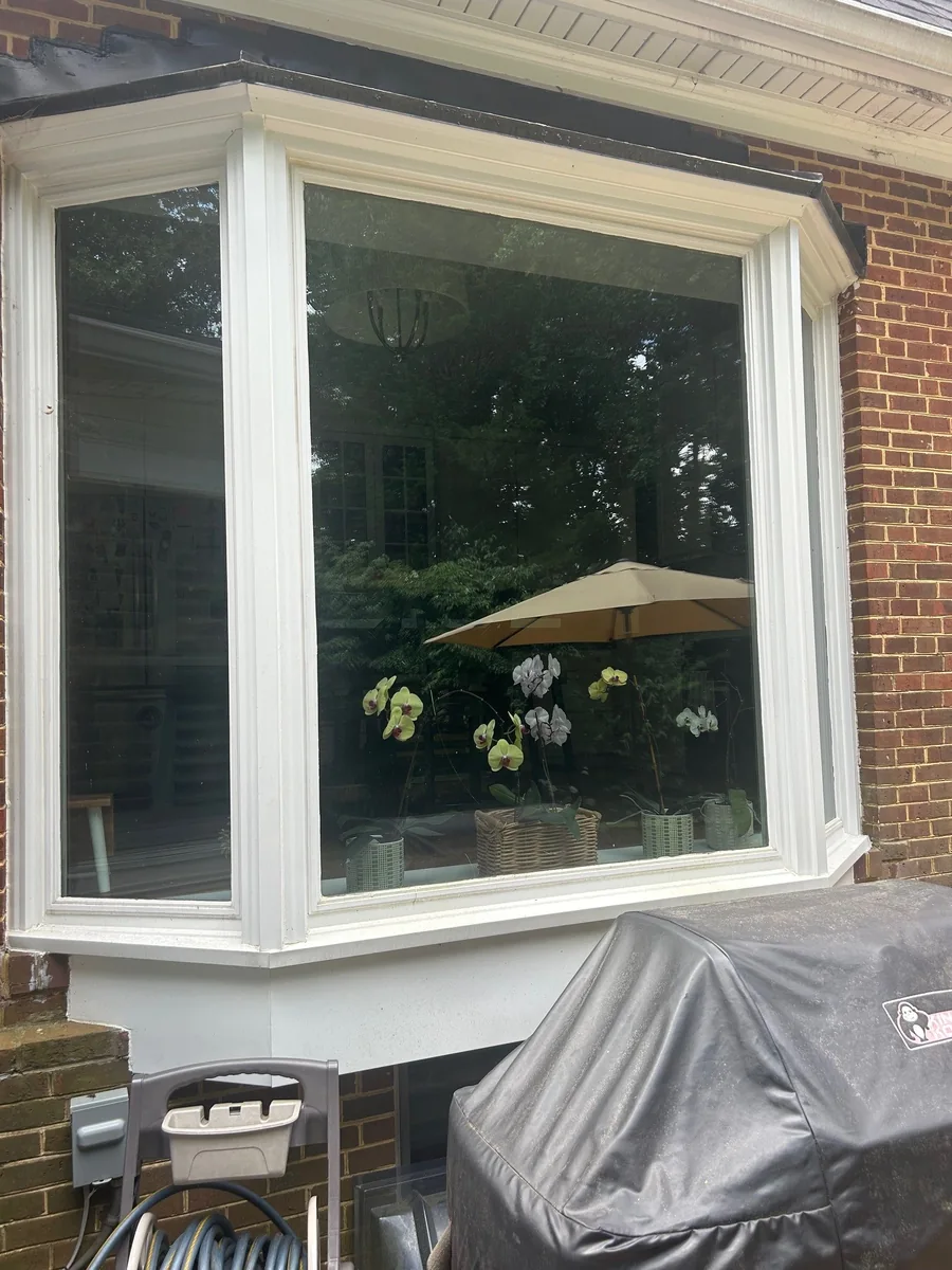 Bay window insulated glass replacement in a white frame on a brick home.